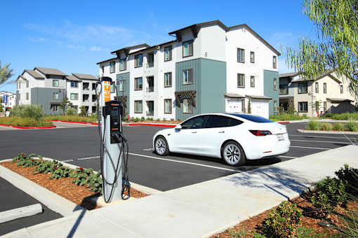 A white car is charging at an electric vehicle charging station.