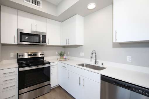 A modern kitchen with white cabinets and stainless steel appliances.