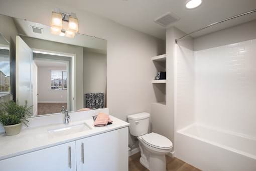A white bathroom with a toilet, sink, and mirror.