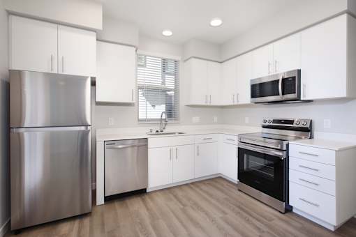 West Sacramento, CA Apartments with In-Unit Washer and Dryer - The Strand - Gourmet Kitchen with Prep Island, Quartz Countertops, Stainless Steel Appliances, White Modern Custom-Wood Cabinetry, and Wood-Style Flooring.