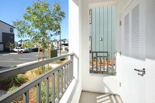 A balcony with a view of a parking lot and buildings.