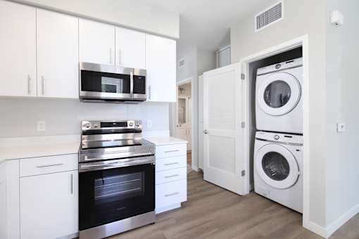 A modern kitchen with white cabinets and stainless steel appliances.