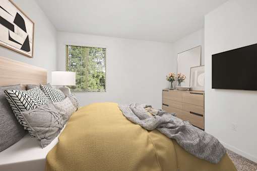A bedroom with a bed covered in a yellow blanket and a white pillow.