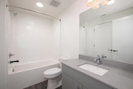 A white bathroom with a toilet, sink, and bathtub.