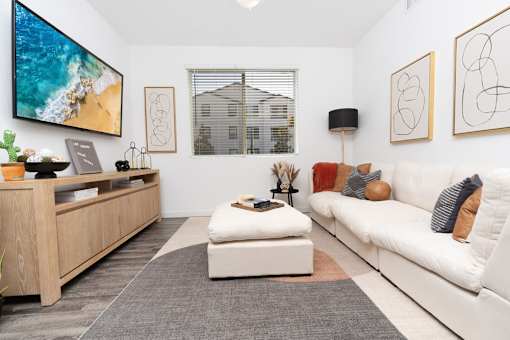 A modern living room with a white couch and a wooden entertainment center.