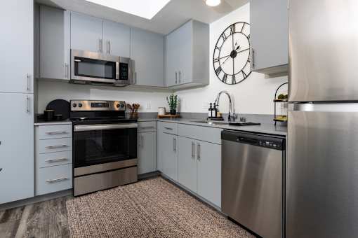 A modern kitchen with stainless steel appliances and a clock on the wall.