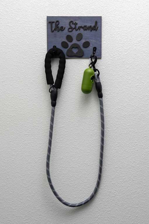 A green pendant hangs from a black cord on a wall.