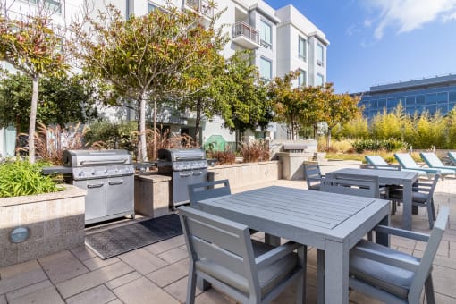 an outdoor patio with tables and chairs and barbecue grills