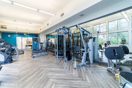 a gym with cardio machines and weights in a building with large windows at Strata at Mission Bay, California, 94158