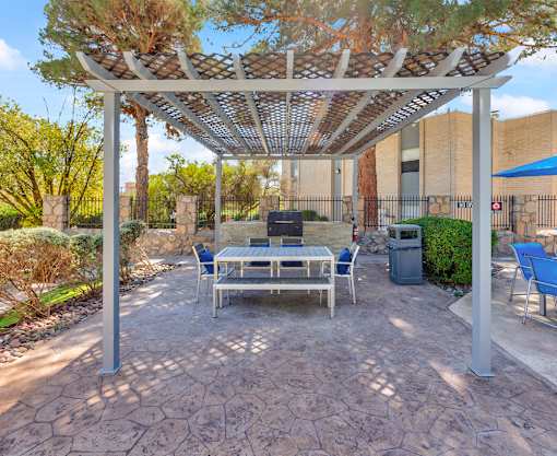A patio with a table and chairs under a pergola.