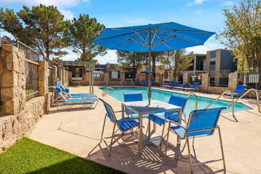 A pool area with blue chairs and an umbrella.