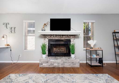 A living room with a fireplace and a flat screen TV mounted above it.