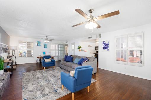 A living room with a blue sofa and a ceiling fan.