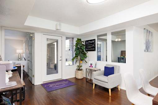 A living room with a white chair and a purple rug.