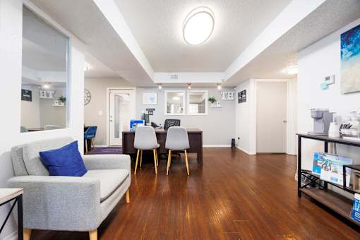 A living room with a grey couch and a wooden floor.