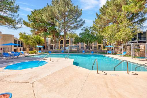 A large swimming pool surrounded by trees and chairs.