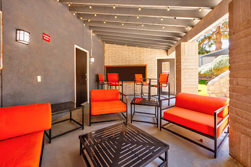 A patio with orange couches and a black coffee table.