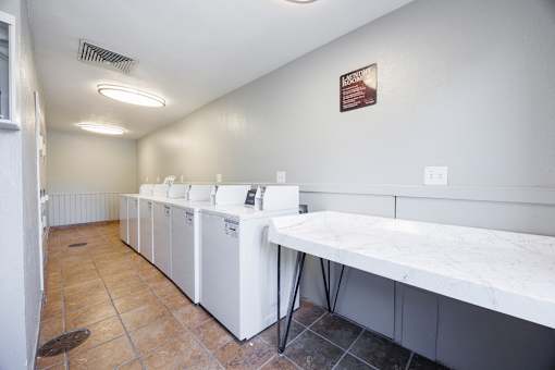 A laundromat with a row of washers and dryers.