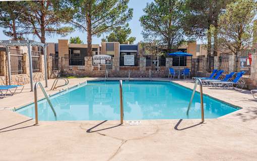 A pool surrounded by trees and a fence.