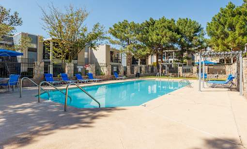 A swimming pool surrounded by trees and a building in the background.