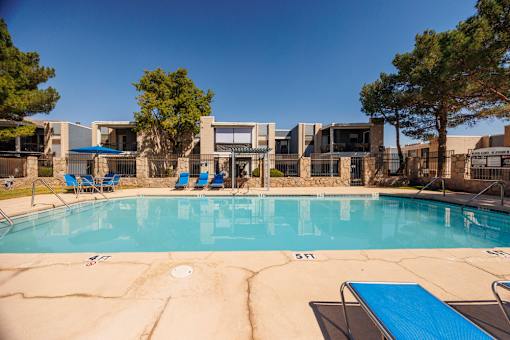 A swimming pool with a blue lounge chair and a building in the background.