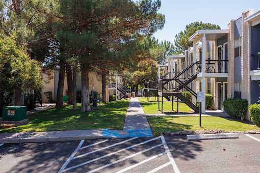 A tree-lined street with apartment buildings on either side.