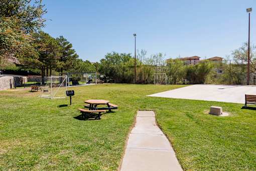 A park with a picnic table and a concrete walkway.