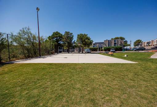 A park with a fence and a building in the background.