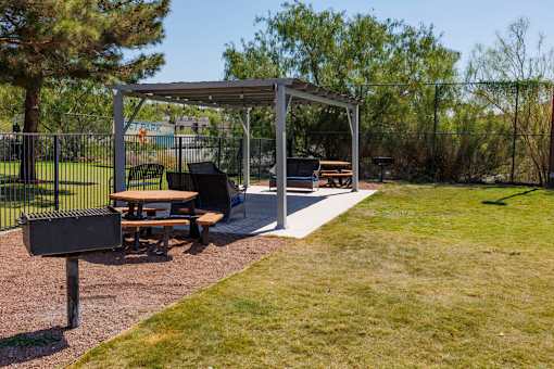 A picnic area with a grill and picnic tables.