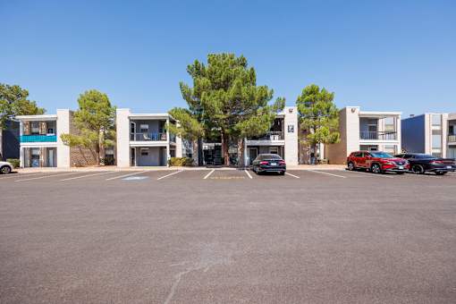 A parking lot with cars and apartment buildings in the background.