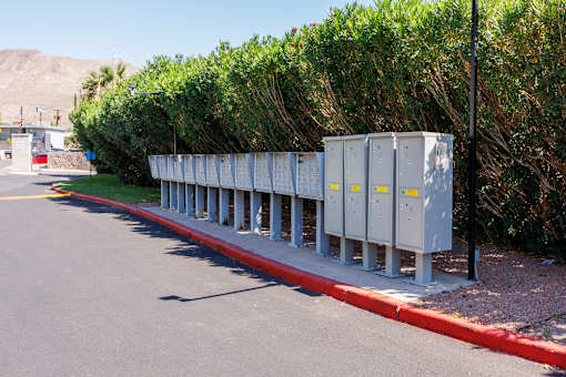 A row of grey utility boxes are lined up on the side of a road.