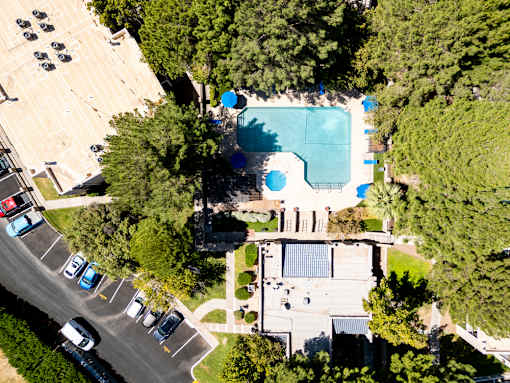 An aerial view of a parking lot with cars and a swimming pool.