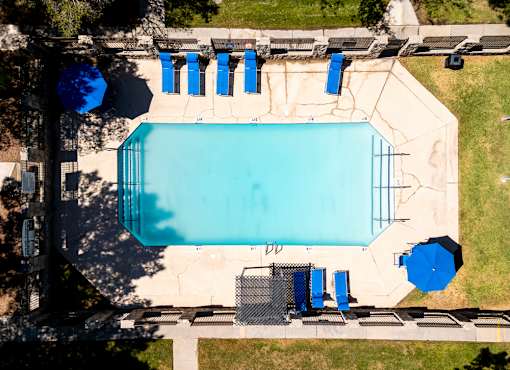 An aerial view of a swimming pool surrounded by blue lounge chairs and umbrellas.