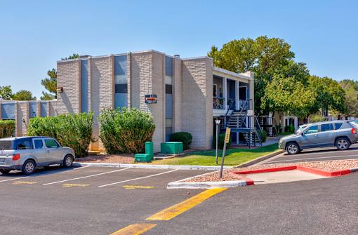 A parking lot with a building in the background and a car parked in the lot.
