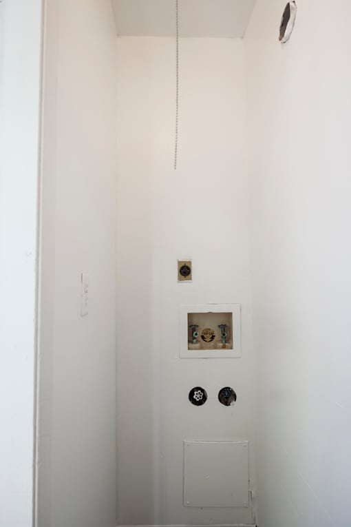 A white bathroom with a toilet and a shower head.