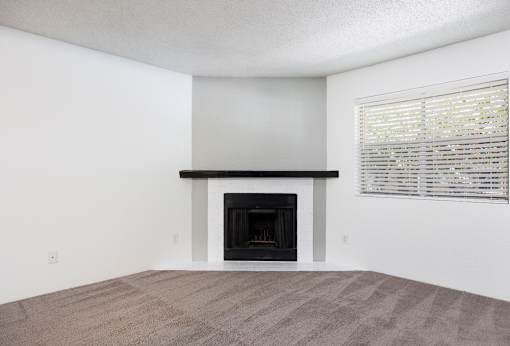A room with a fireplace and a window with blinds.