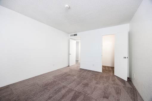 A carpeted room with two doors and a window.