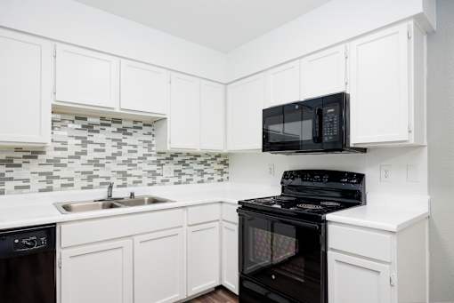 A black microwave oven is on top of a black stove.