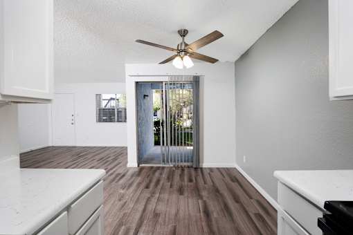 A room with a ceiling fan and wooden flooring.