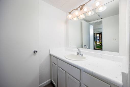 A bathroom with a white sink and mirror.