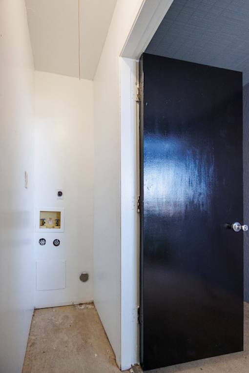 A black door is in a white room.