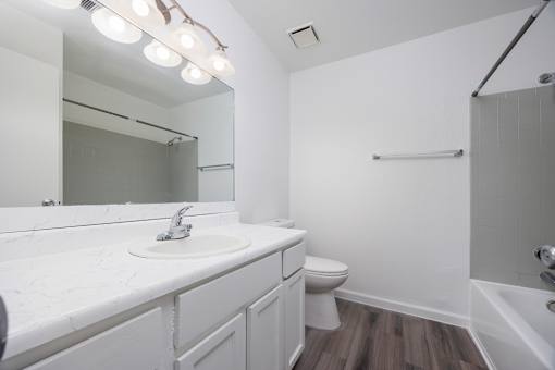 A white bathroom with a sink, toilet, and a mirror.