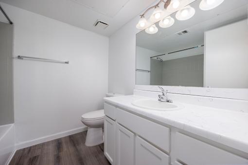A white bathroom with a toilet, sink, and mirror.