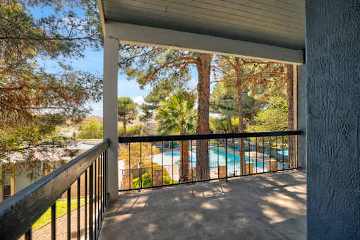 A balcony with a pool in the background.