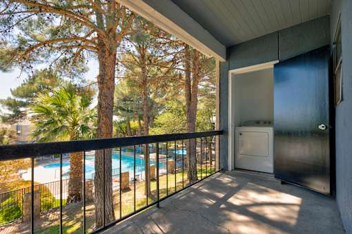 A balcony with a pool and trees in the background.