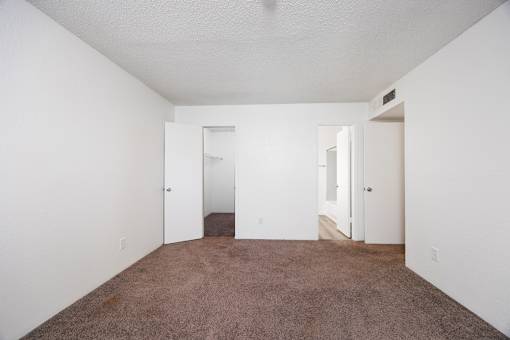 A room with carpeted floor and three doors.
