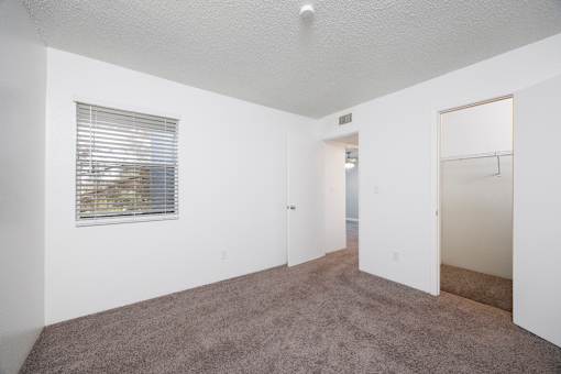 A room with a carpeted floor and a window with blinds.