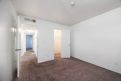 A room with white walls and carpeted floor with two doors.