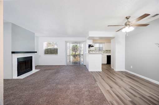 A spacious living room with a fireplace and a ceiling fan.