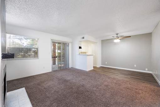 A spacious room with a carpeted floor and a ceiling fan.